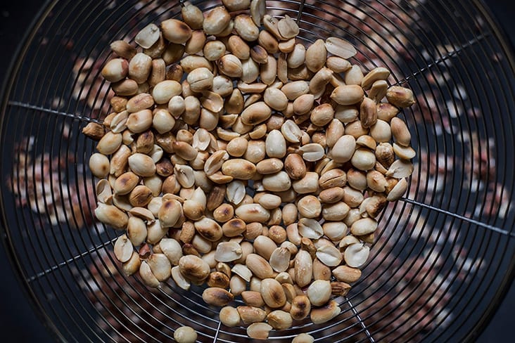 Separate the roasted peanuts from their skins using a large sieve.