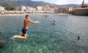 A boy jumps into water on a half-empty city beach as coronavirus disease (COVID-19) heavily affects tourism in Budva, Montenegro,