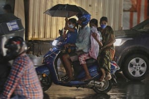 A family rides a motorcycle in the rain in Hyderabad.