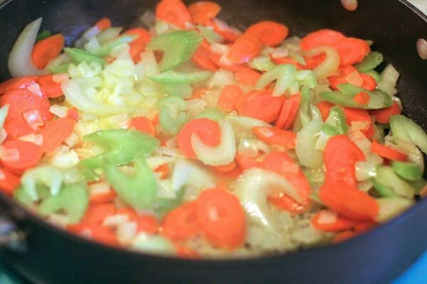 Vegetables for a chicken pot pie casserole cooking in a skillet.