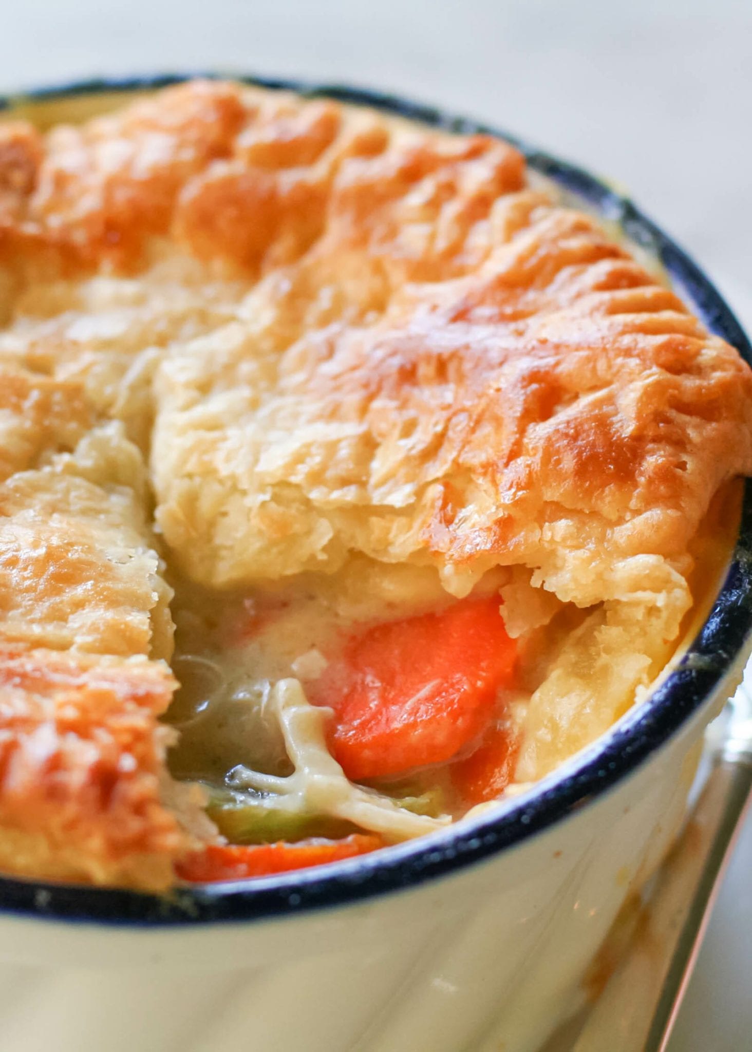 A chicken pot pie with a golden crust and creamy filling is in a ramekin.