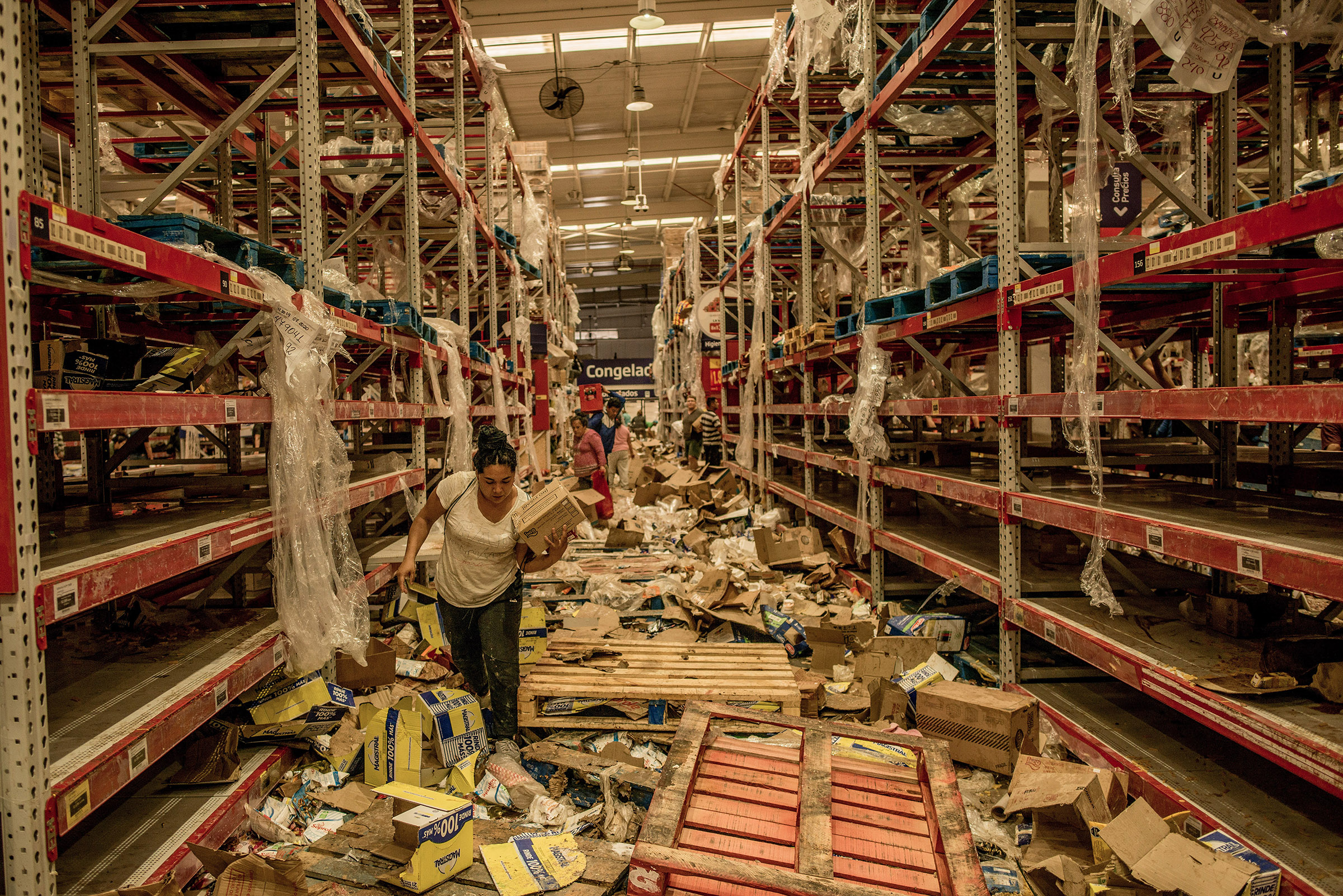 People look through the remains of a looted supermarket in Santiago, Chile, on Oct. 23, 2019.