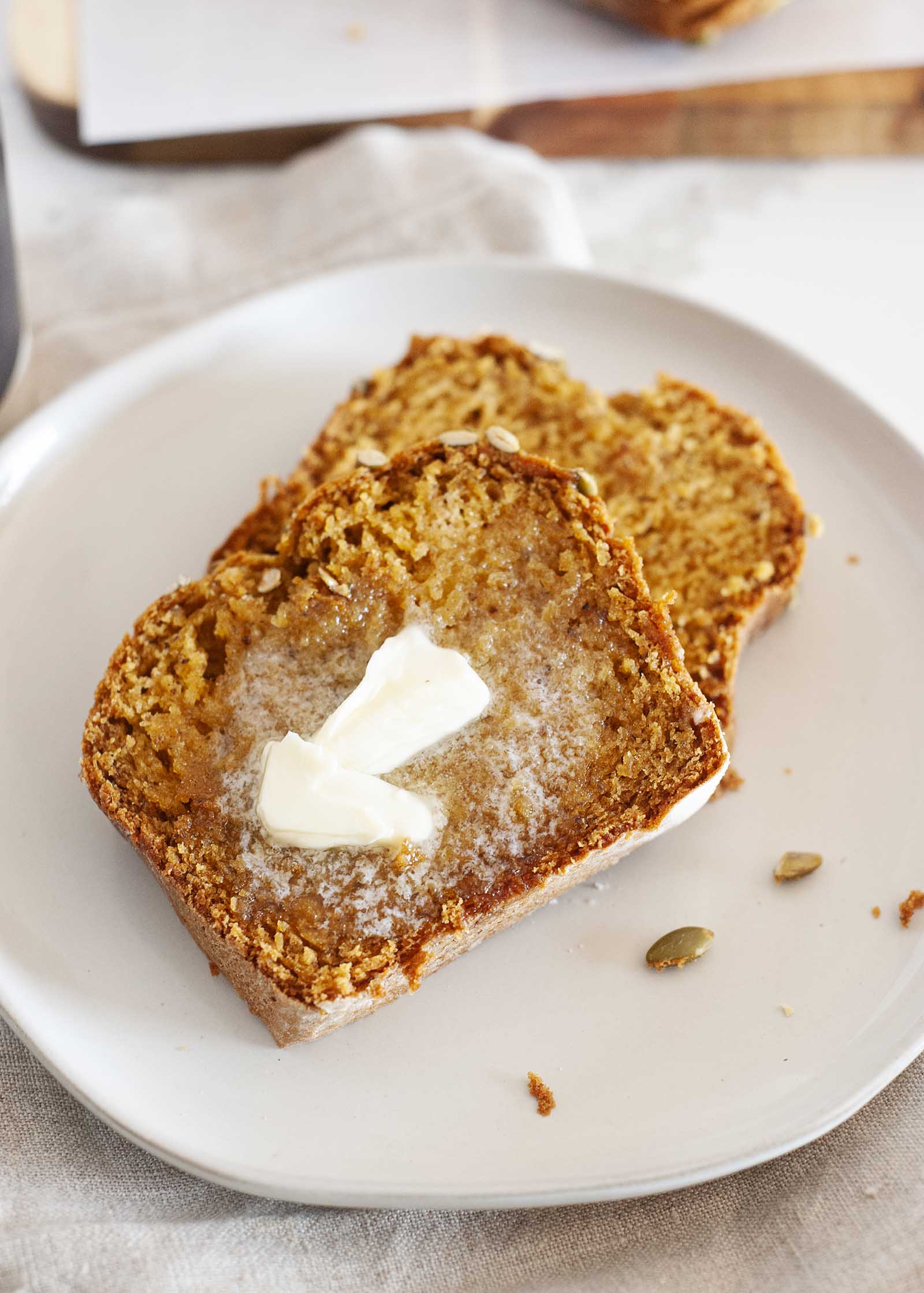 Two stacked slices of Dairy-Free Pumpkin Bread on a white plate with butter melting on top.