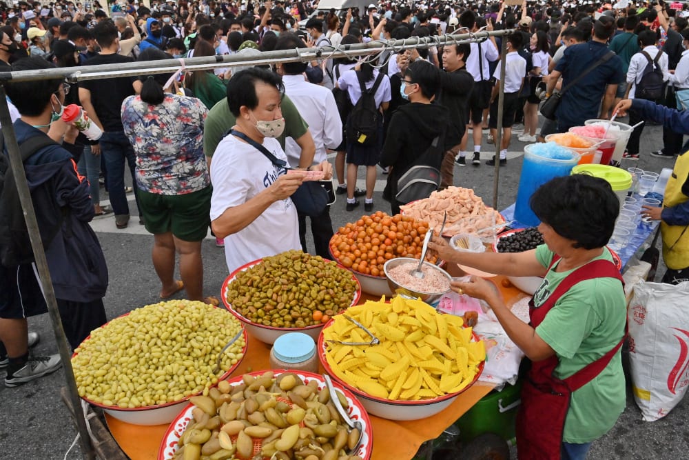 A man buying preserved fruit from a street food vendor during an anti-government rally by pro-democracy protesters in Bangkok, October 21, 2020. — AFP pic