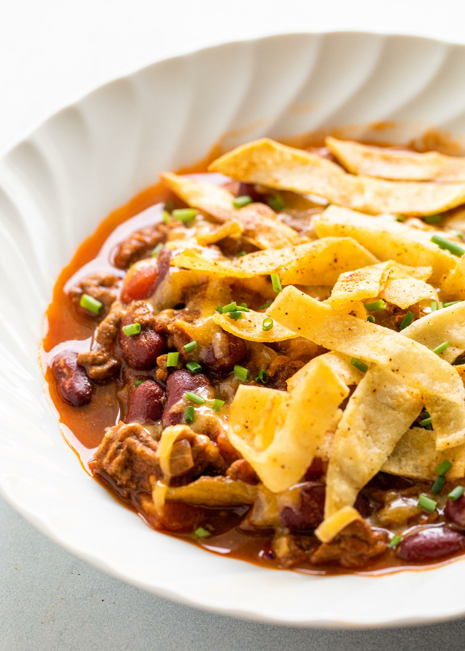 The Best Slow Cooker Chili topped with fried tortilla strips in a white bowl.