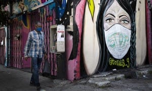 A man wearing a face mask walks past a mural in South Central Los Angeles. In November 2020, California is reaching an unwelcome coronavirus record: its 1 millionth positive test.