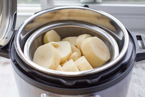 Place the steamer basket of sliced potatoes into the instant pot insert for making mashed potatoes