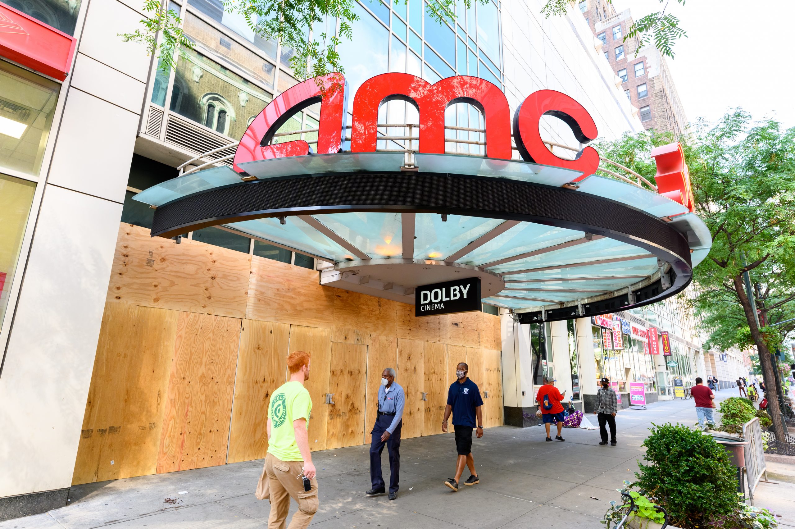 People walk outside the newly boarded AMC 34th Street 14 movie theater
