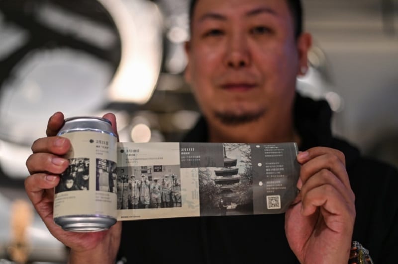 Wang Fan, founder of the No. 18 Brewery, posing with one of his beers with images of the city's fight against the Covid-19 coronavirus in Wuhan ― AFP pic