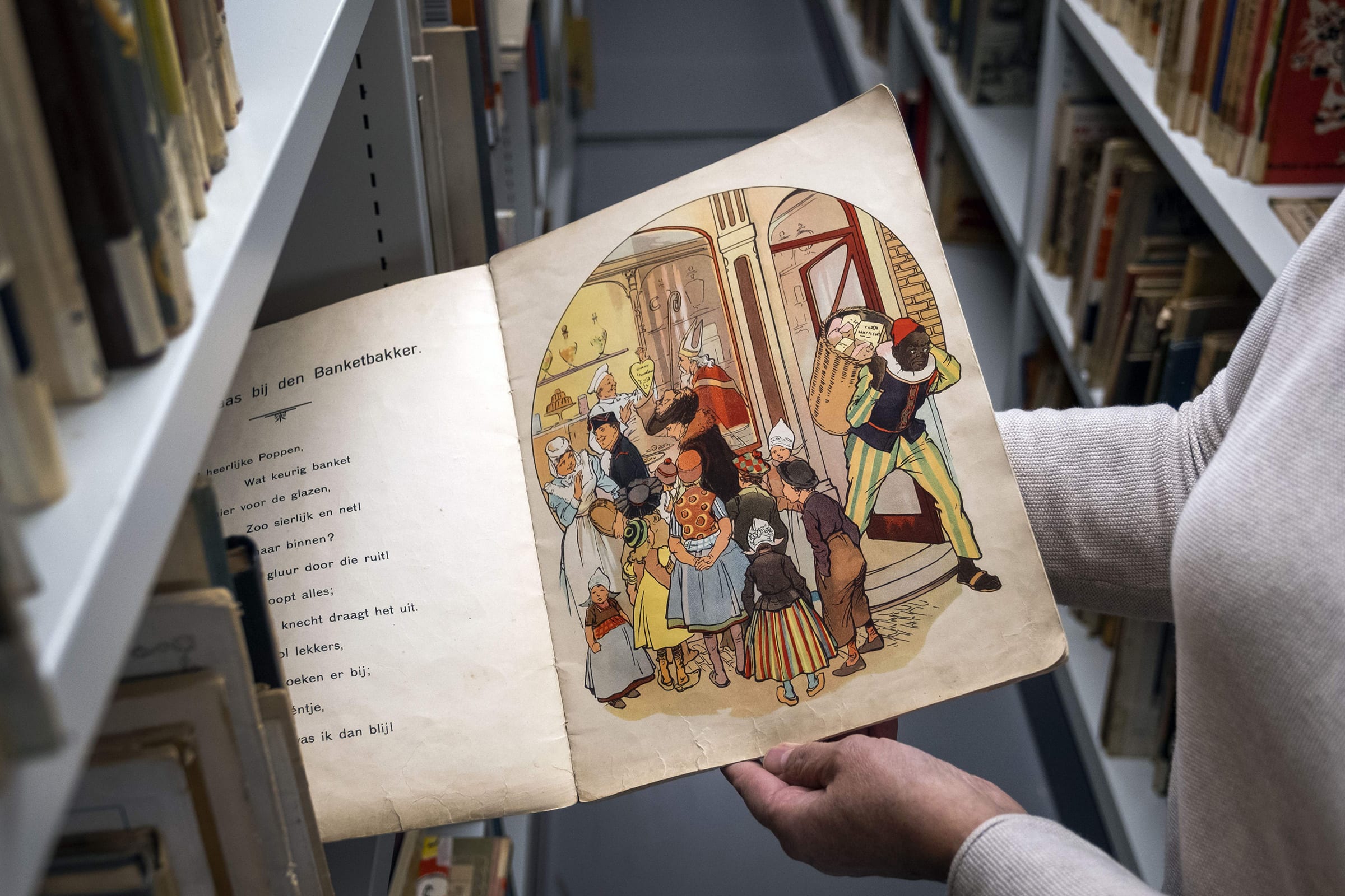 An Amsterdam Public Library employee with a book about Sinterklaas and Zwarte Piet (Black Pete) in Amsterdam, on Nov. 12, 2020.