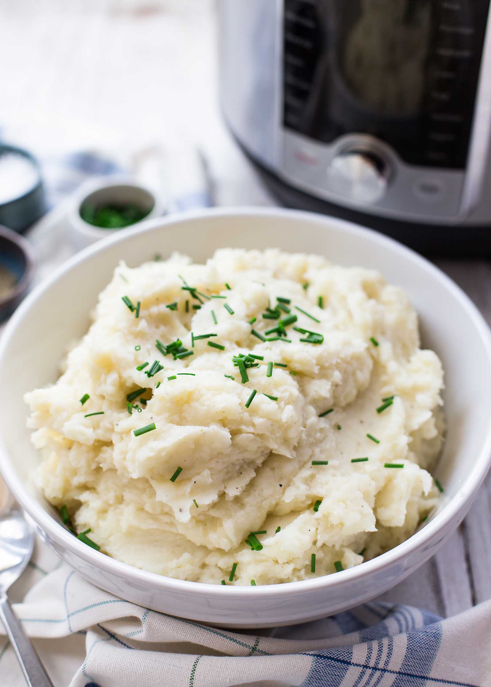 Bowl of pressure cooker mashed potatoes with an instant pot in the background