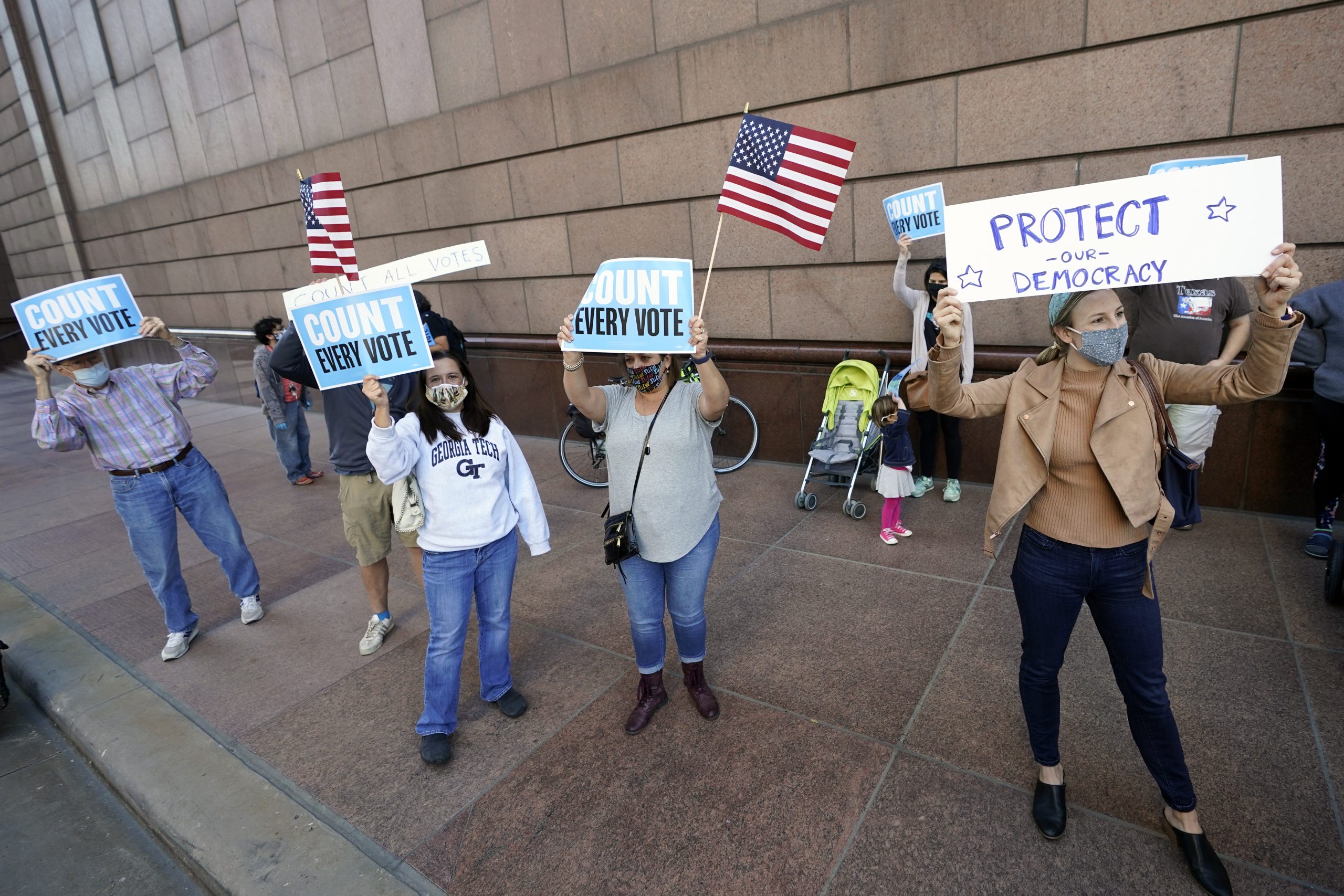 Demonstrators stand across the street from the federal courthouse in Houston, Monday, Nov. 2, 2020, before a hearing in federal court involving drive-thru ballots cast in Harris County.
