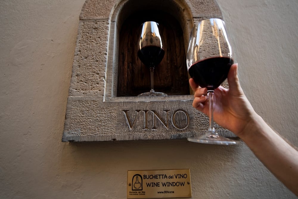 A person holds a glass of wine next to a ‘buchetta del vino’. — AFP pic