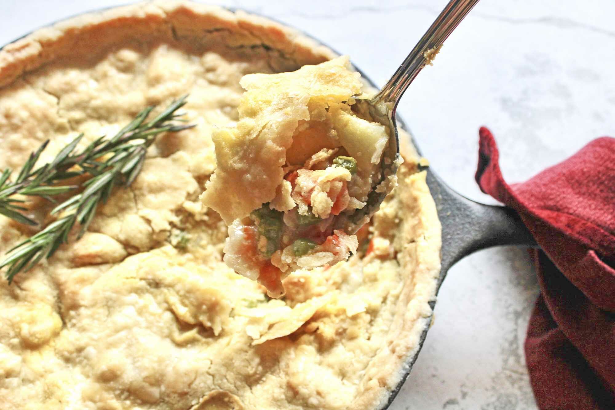 An Easy Vegetarian Pot Pie in a cast iron skillet and a fork scooping some pie out of the skillet.