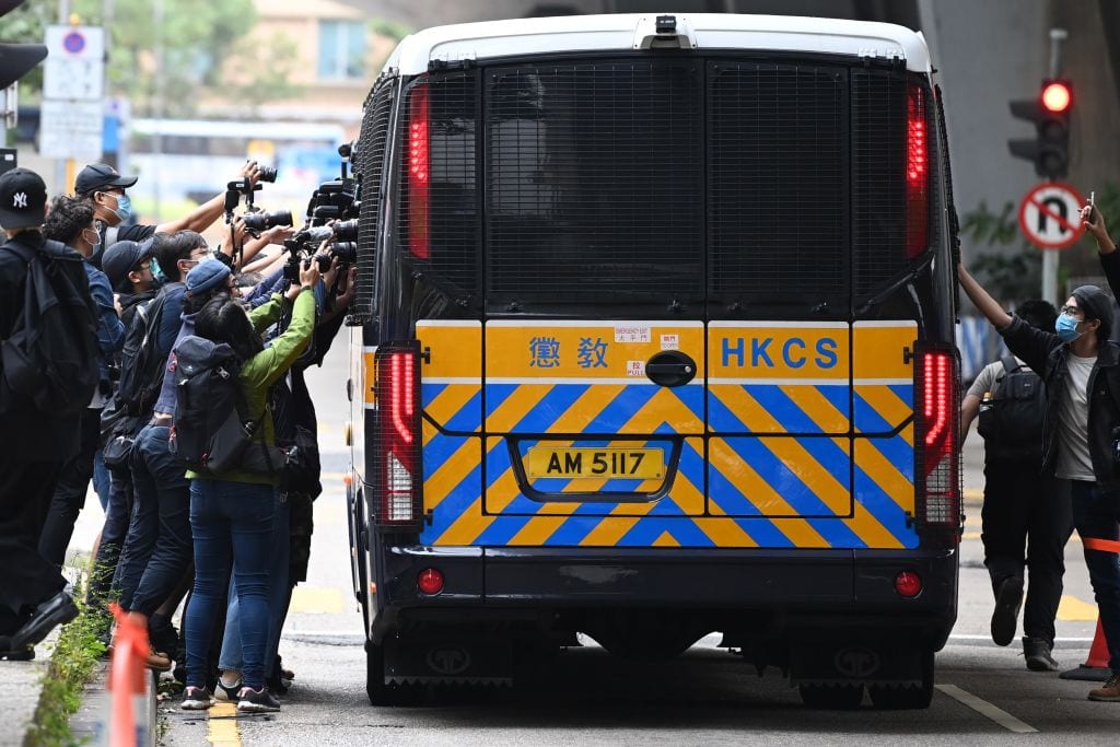 Members of the media surround a correctional services bus purportedly carrying pro-democracy activists Agnes Chow, Ivan Lam and Joshua Wong as it leaves court in Hong Kong on November 23, 2020.